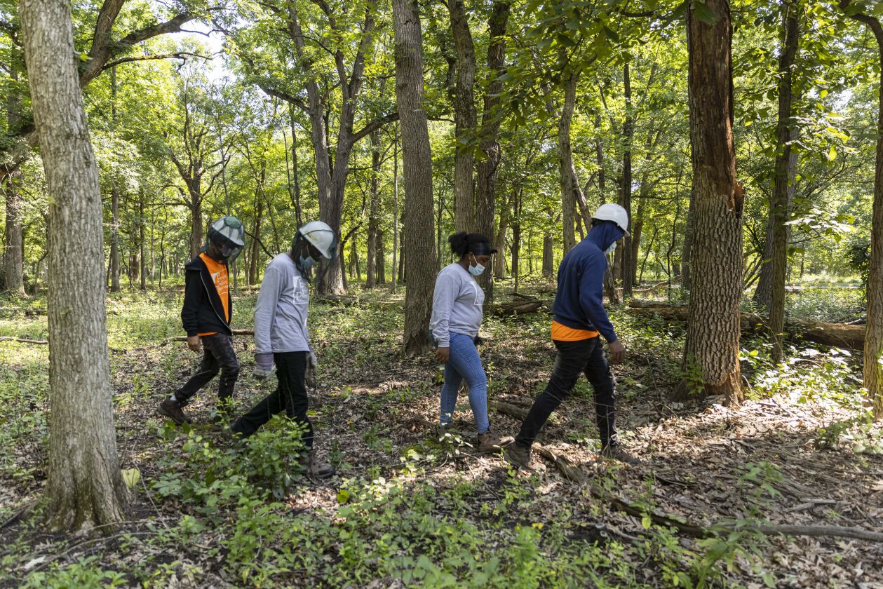 Crew members walk back to the shelter for a break after clearing brush. The county program is educational and assures much-needed maintenance is done at the forest preserves.